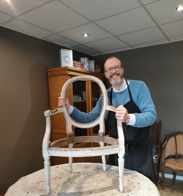 David Comptdaer dans son atelier avec un fauteuil en cours de restauration
