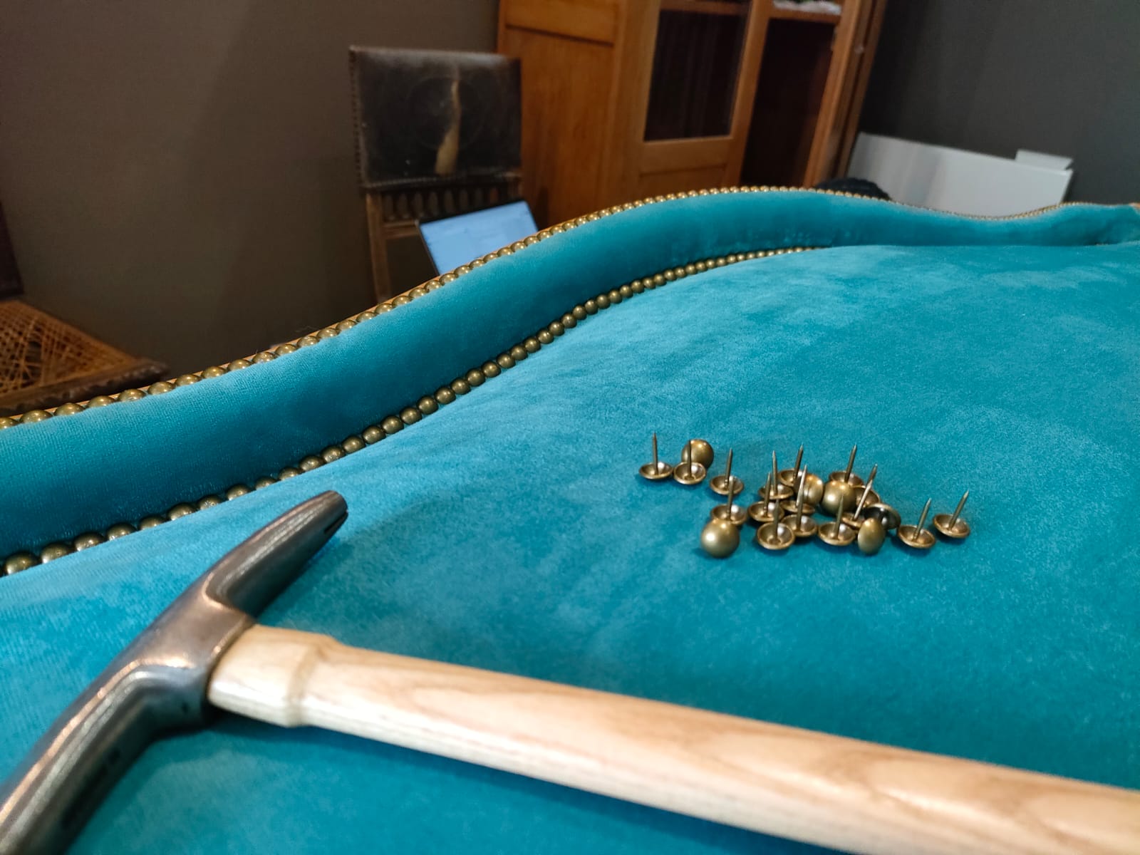 Pose traditionnelle de clous décoratifs sur un velours turquoise